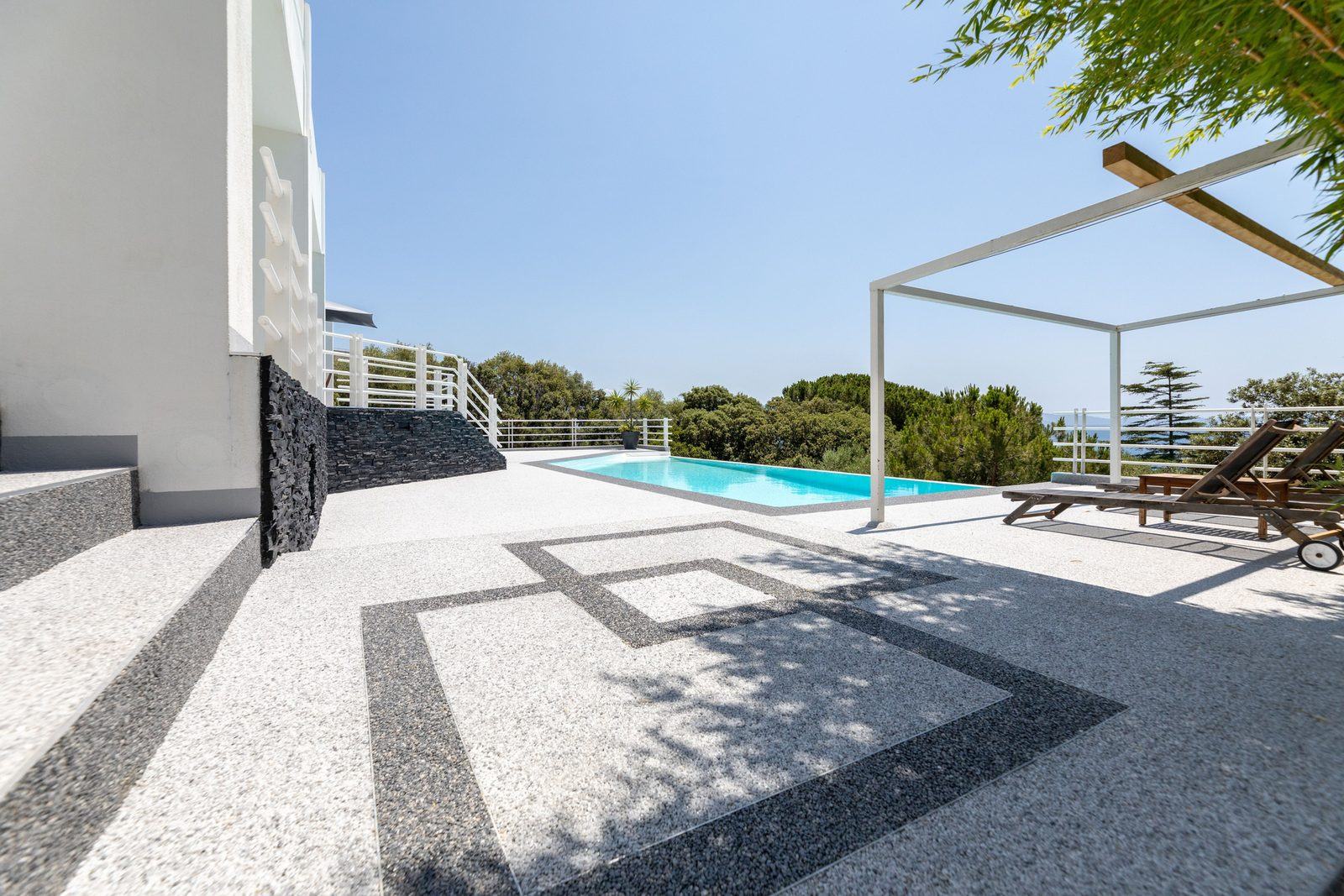 Terraza de piscina con pavimento Resineo blanco y diseño geométrico a medida